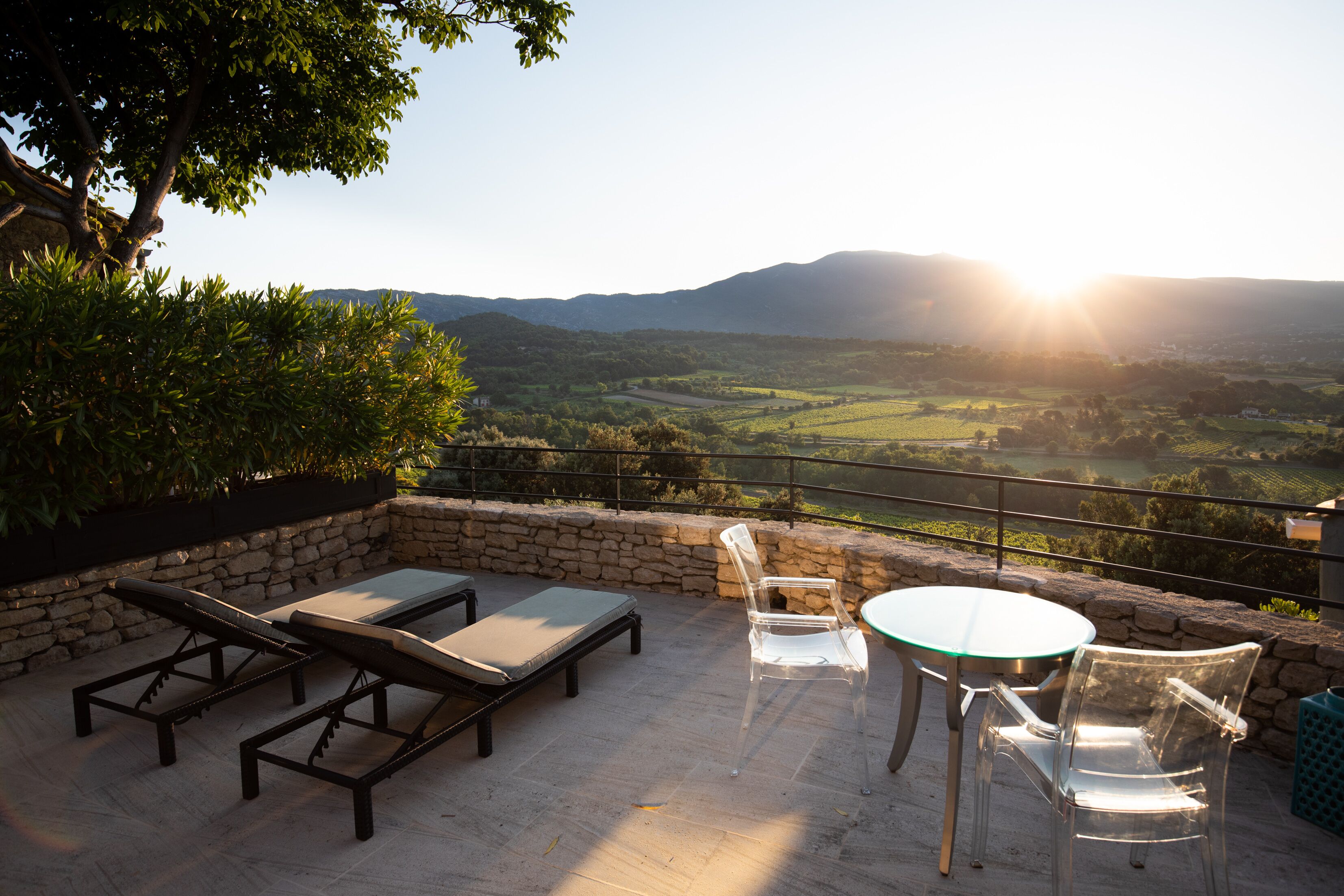 Un patio exterior con sillones de descanso y una mesa, con vistas a un valle y montañas panorámicos.