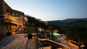 Une terrasse en bois avec une piscine, des murs en pierre et un escalier menant à un bâtiment.