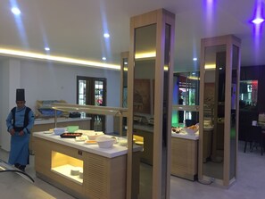 A modern breakfast bar with a variety of food items and a chef in uniform. - Miray Hotel (Marmaris)