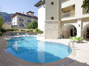 Una piscina al aire libre, sombrillas, sillones reclinables de piscina