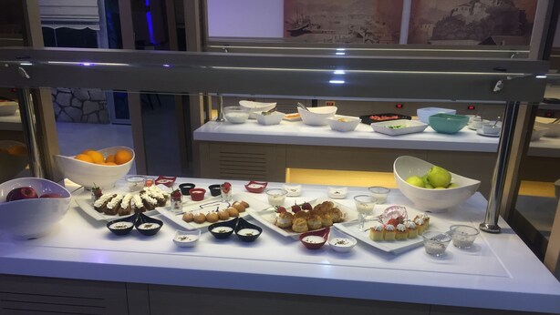 A buffet with various food items and bowls, including fruits and desserts.