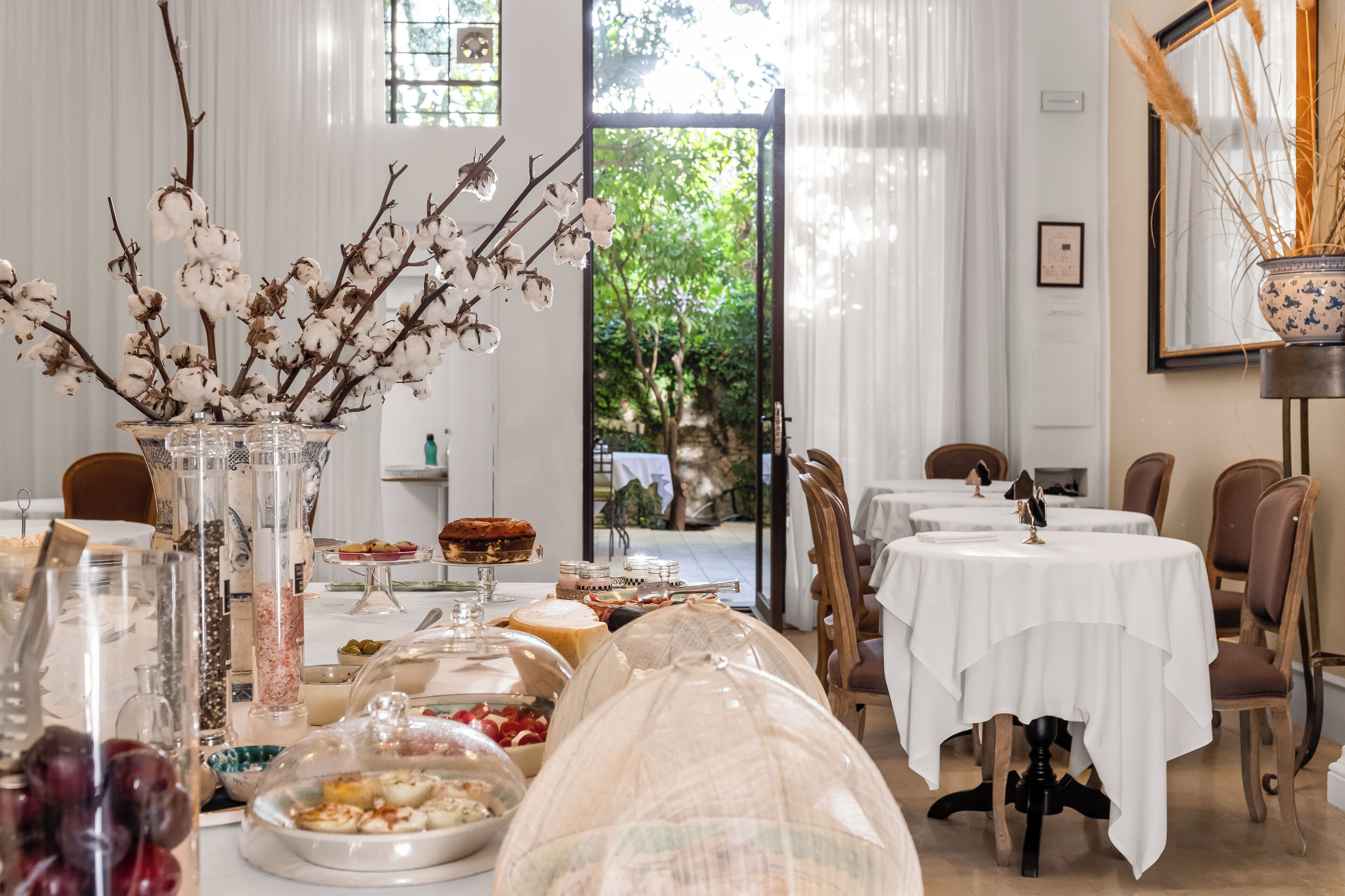 A dining area with tables, chairs, and a view of greenery outside.