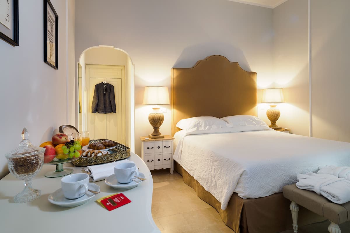 A hotel room with a bed, bedside lamps, a breakfast tray, and a mirror.