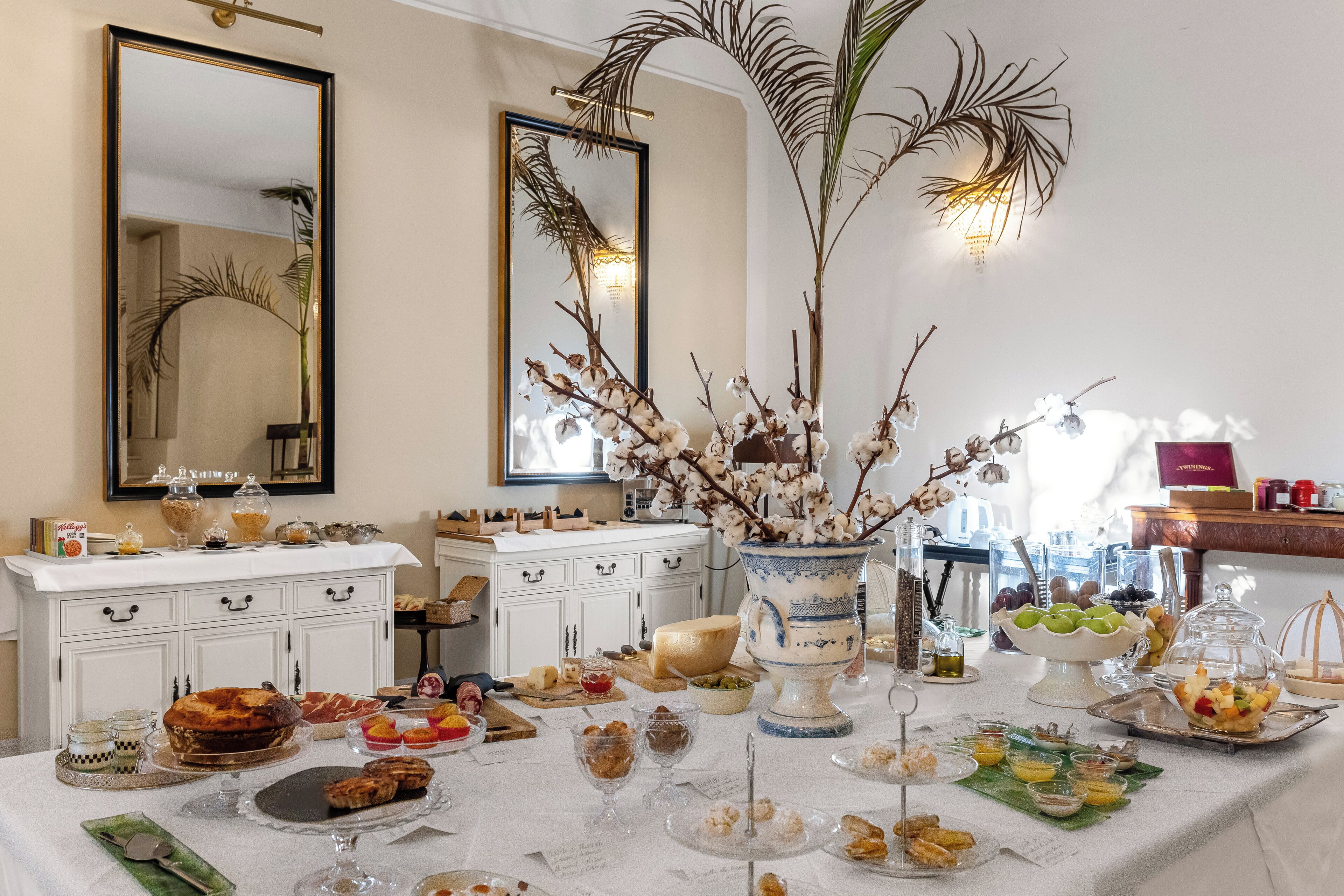 Una mesa de buffet con diversos alimentos, un armario blanco y dos espejos grandes.