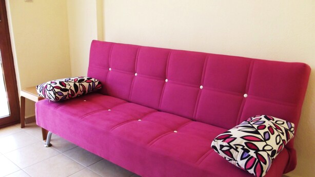 A pink sofa with two patterned pillows and a tiled floor. - Murat Apart Hotel (Marmaris)