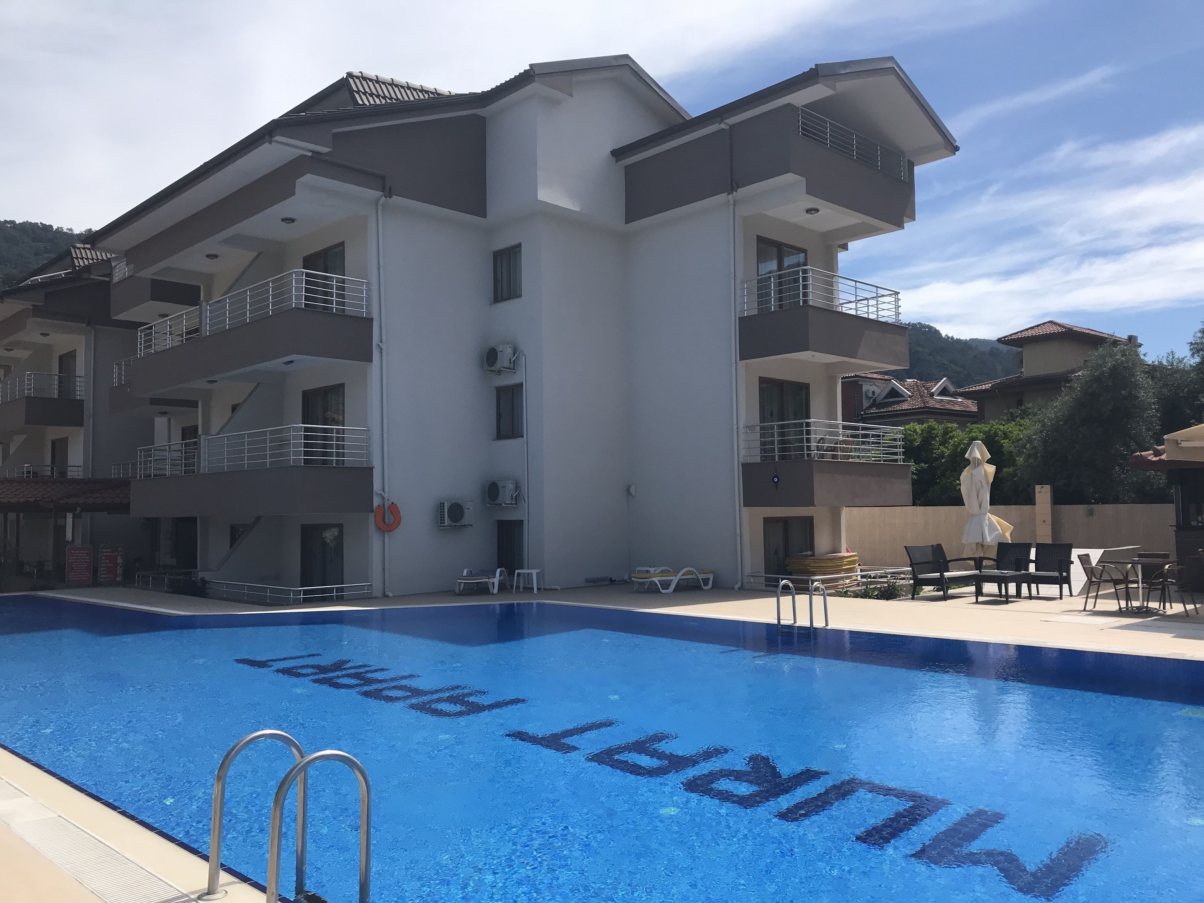 Ein modernes Hotel mit Schwimmbad, mehreren Balkonen und Außenbereich mit Sitzgelegenheiten.