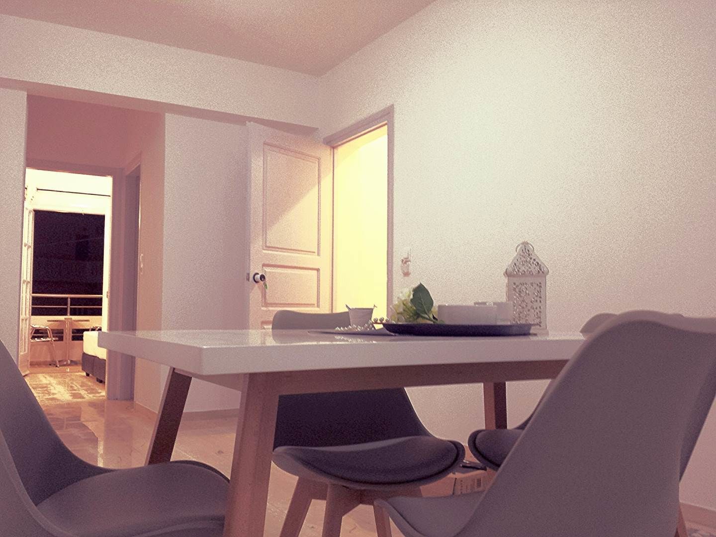 Un espace repas comprenant une table et des chaises, une porte et une vue sur une autre pièce.