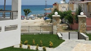 Zona residencial con vista al mar, un sendero pavimentado y un pequeño jardín con flores amarillas.