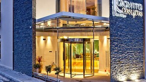Um hotel moderno com fachada de pedra, entrada de vidro e uma placa com a inscrição