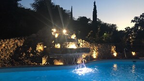 Piscina com cachoeira e paredes de pedra.