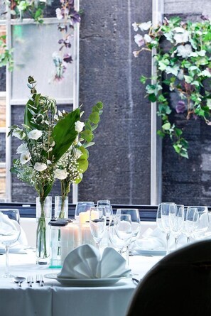 A dining table set with white tableware and a centerpiece of white flowers and greenery. - Kalavrita Canyon Hotel & Spa (Kalavrita)