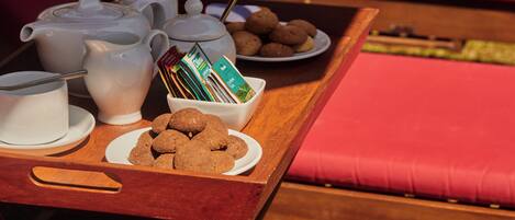 A breakfast tray with tea, coffee, cookies, and a book on a wooden table.
