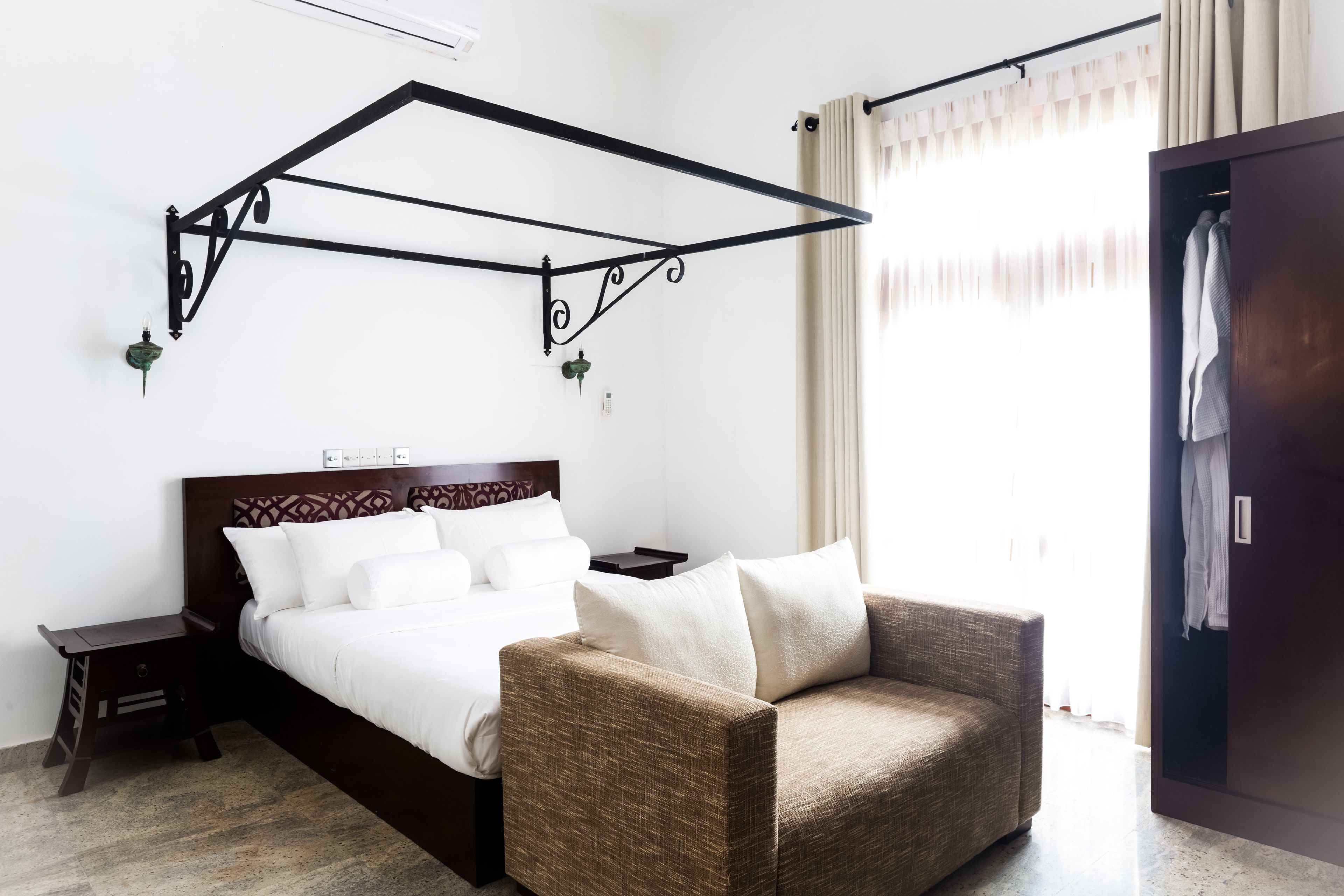 Una camera d'albergo con un letto, un comodino, una sedia e un armadio.