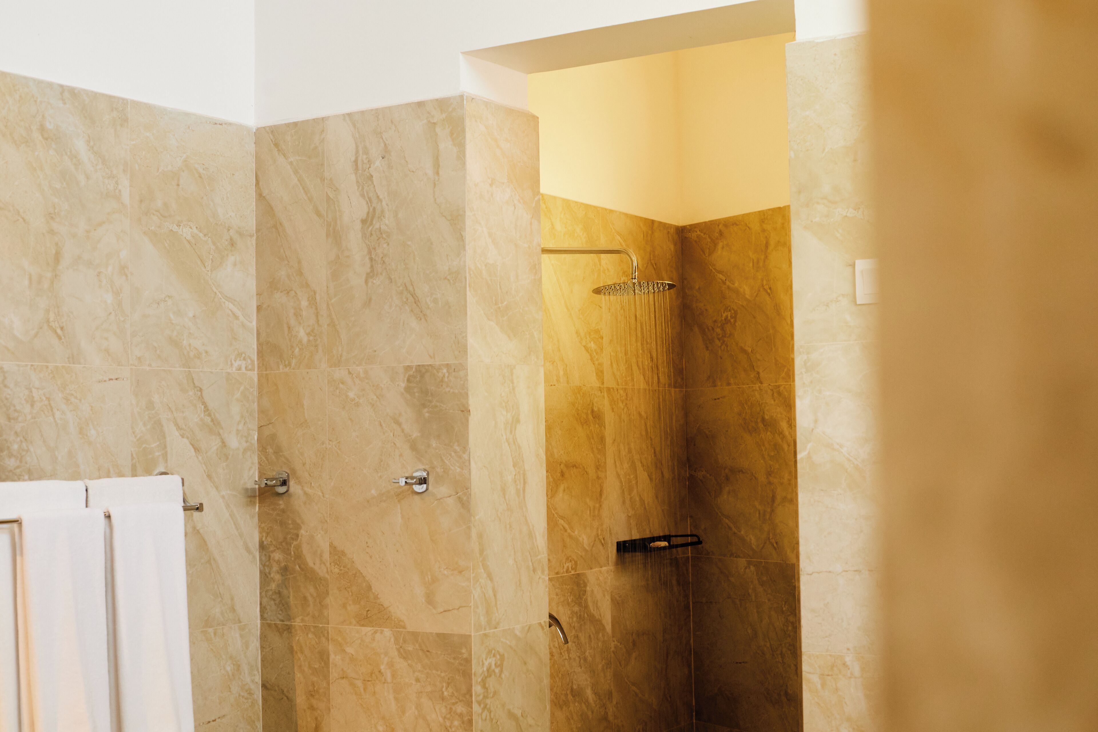 Un baño moderno con ducha, azulejos de mármol y un perchero.