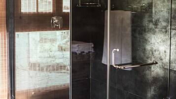 Una doccia moderna con cabina in vetro, un portasciugamani e un piccolo ripiano.