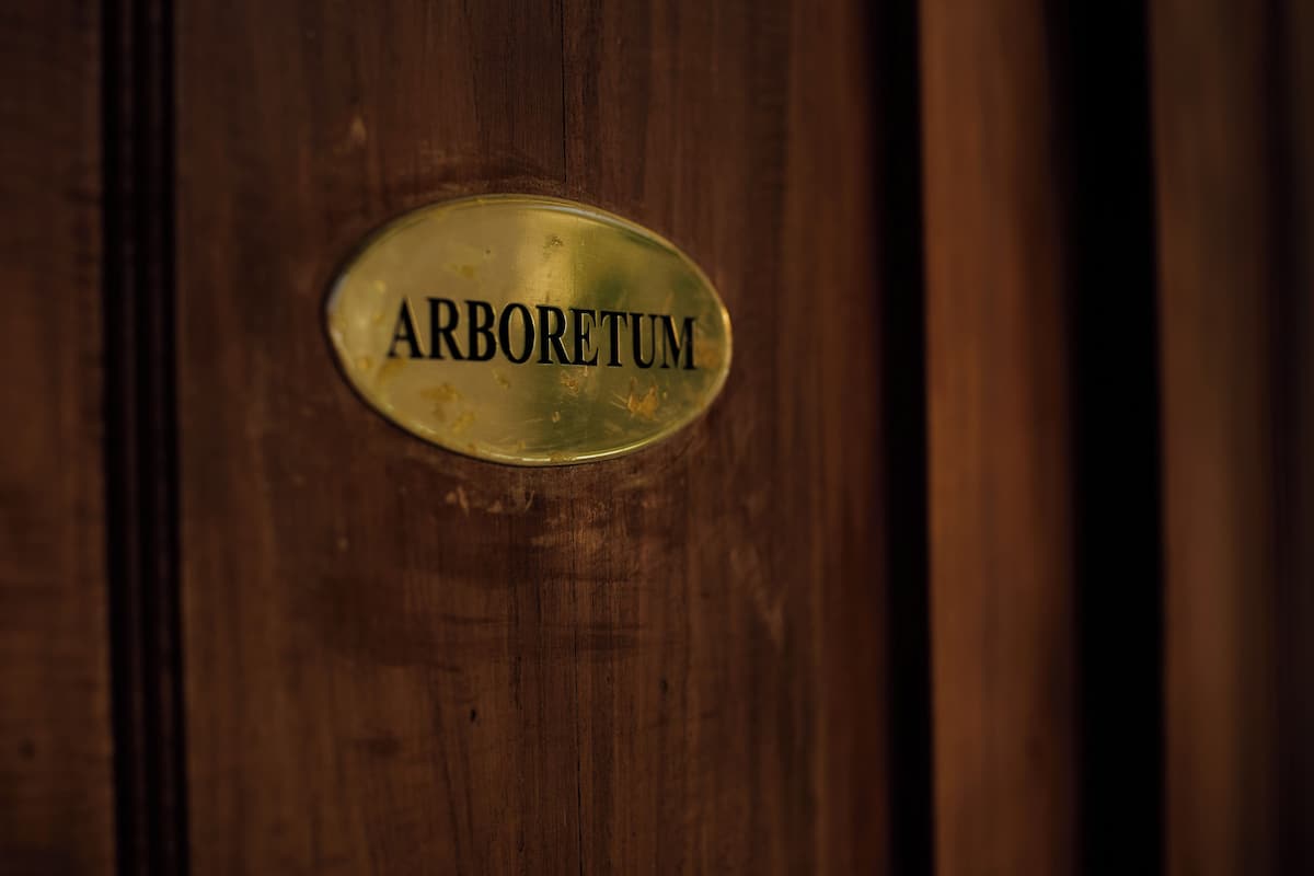 Una porta in legno con una targa di ottone con su scritto "ARBORETUM".