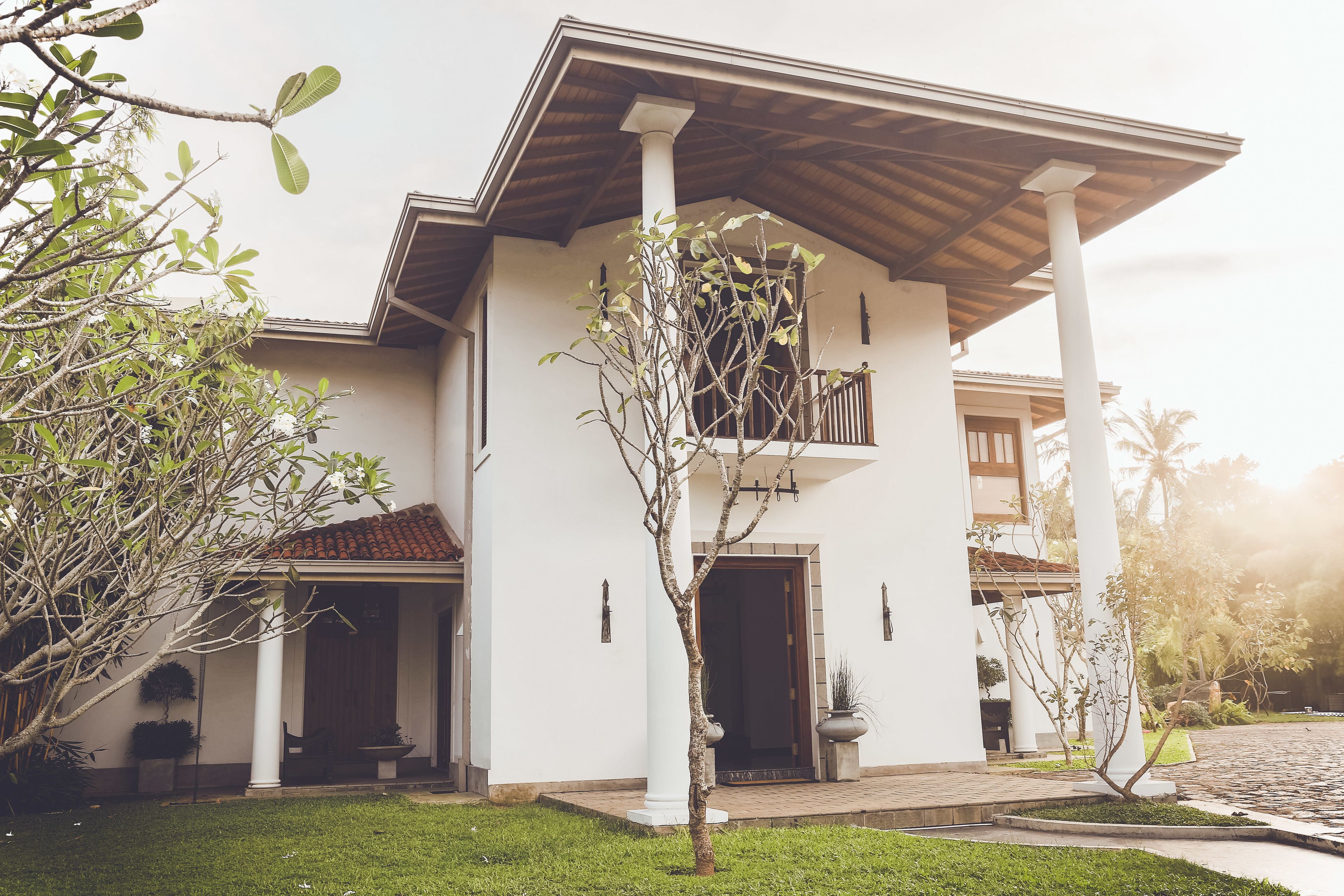 A two-story house with a balcony, a covered porch, and a well-maintained lawn.