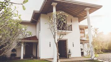 A two-story house with a balcony, a covered porch, and a well-maintained lawn.