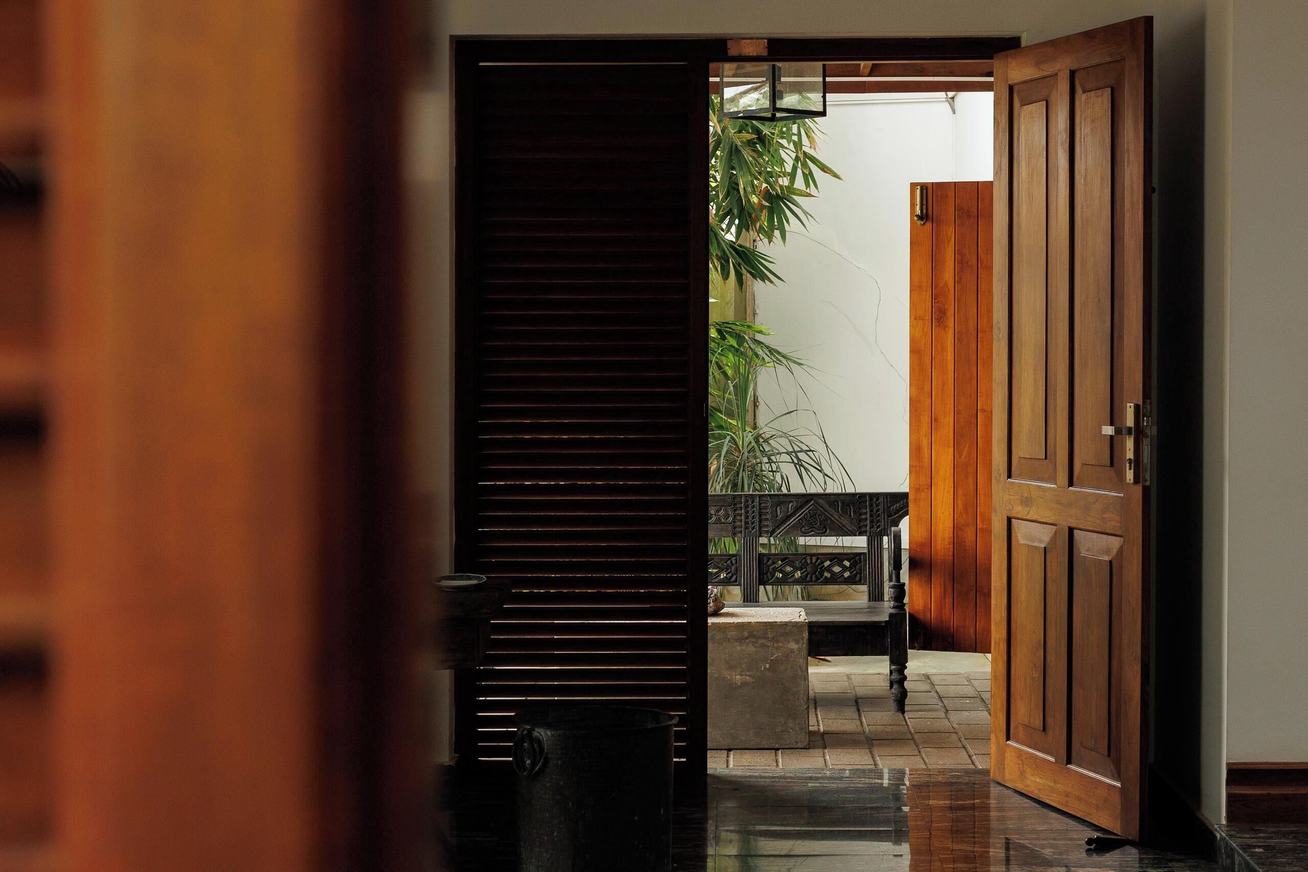 A hallway with a wooden door, a bench, and a potted plant.