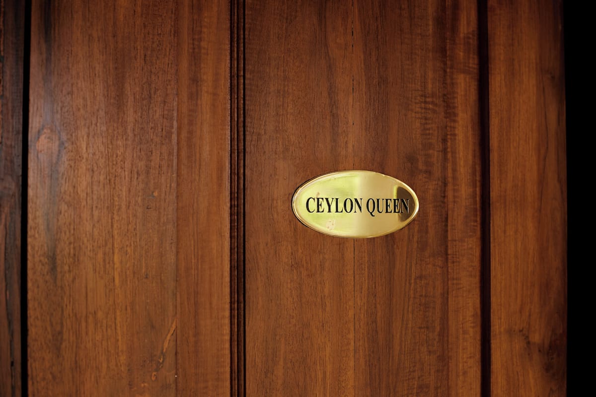 Una porta in legno con una targhetta di ottone che riporta la scritta 'CEYLON QUEEN'.