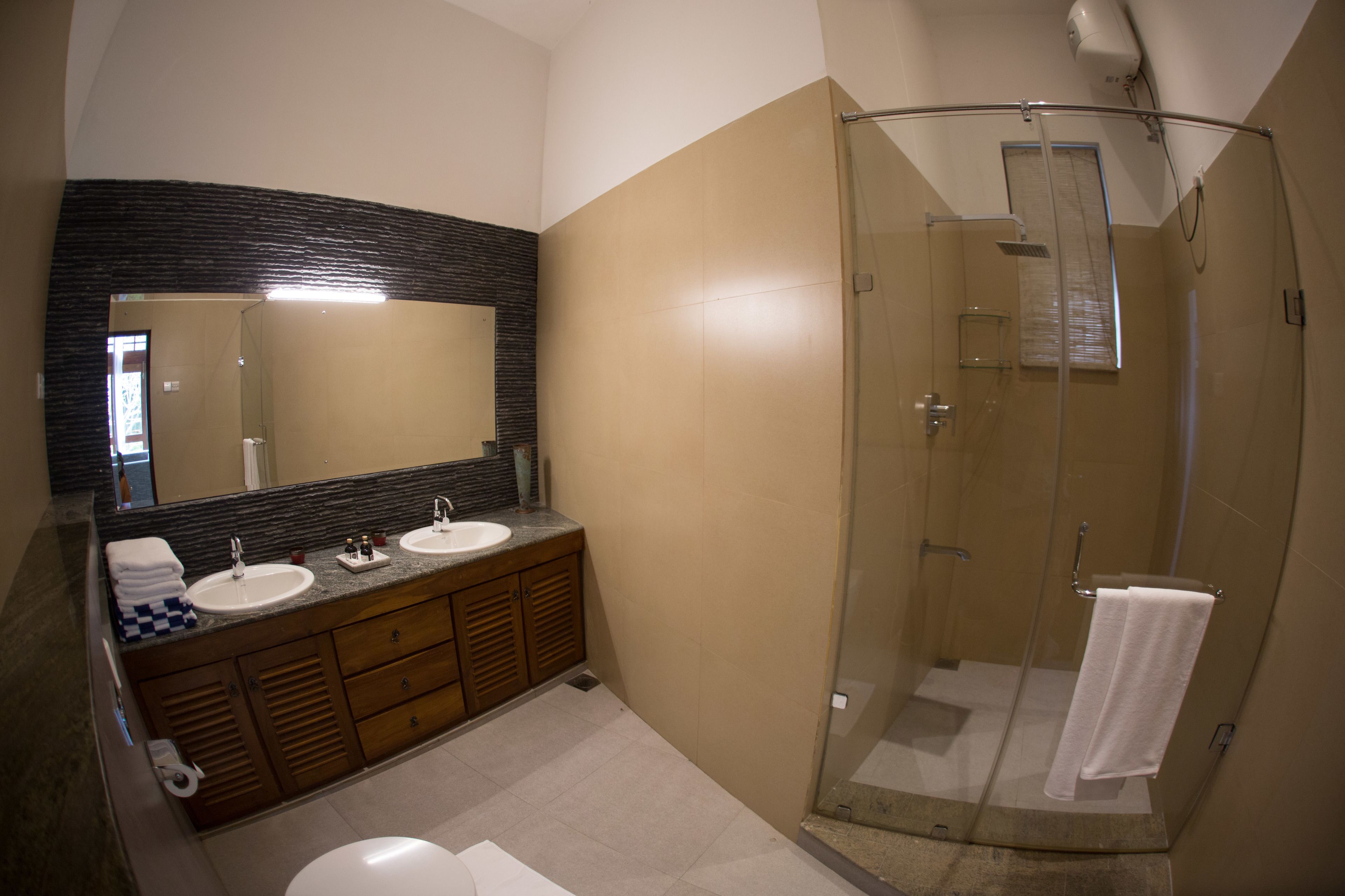 A modern bathroom with a glass-enclosed shower, a large mirror, and a vanity with two sinks.