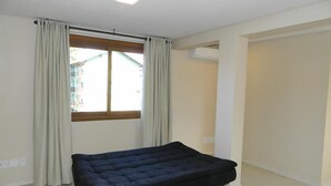 A room with a large window, a bed, and an air conditioning unit. - Residencial Maria Libardi (Gramado)