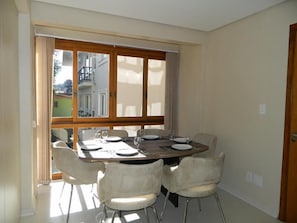 A dining area with a large table set for four, surrounded by four chairs. - Residencial Maria Libardi (Gramado)