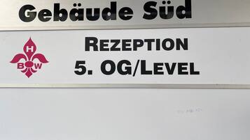 A sign with "Gebäude Süd" and "RECEPTION 5. OG/LEVEL" indicating a building and reception level.