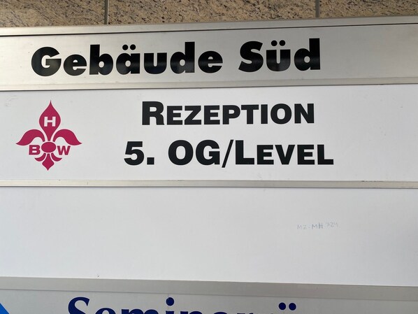 Un panneau indiquant « Gebäude Süd » et « RECEPTION 5. OG/LEVEL », signalant un bâtiment et le niveau où se trouve la réception.