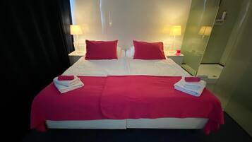 A double bed with red and white bedding, two bedside lamps, and a mirror on the wall.