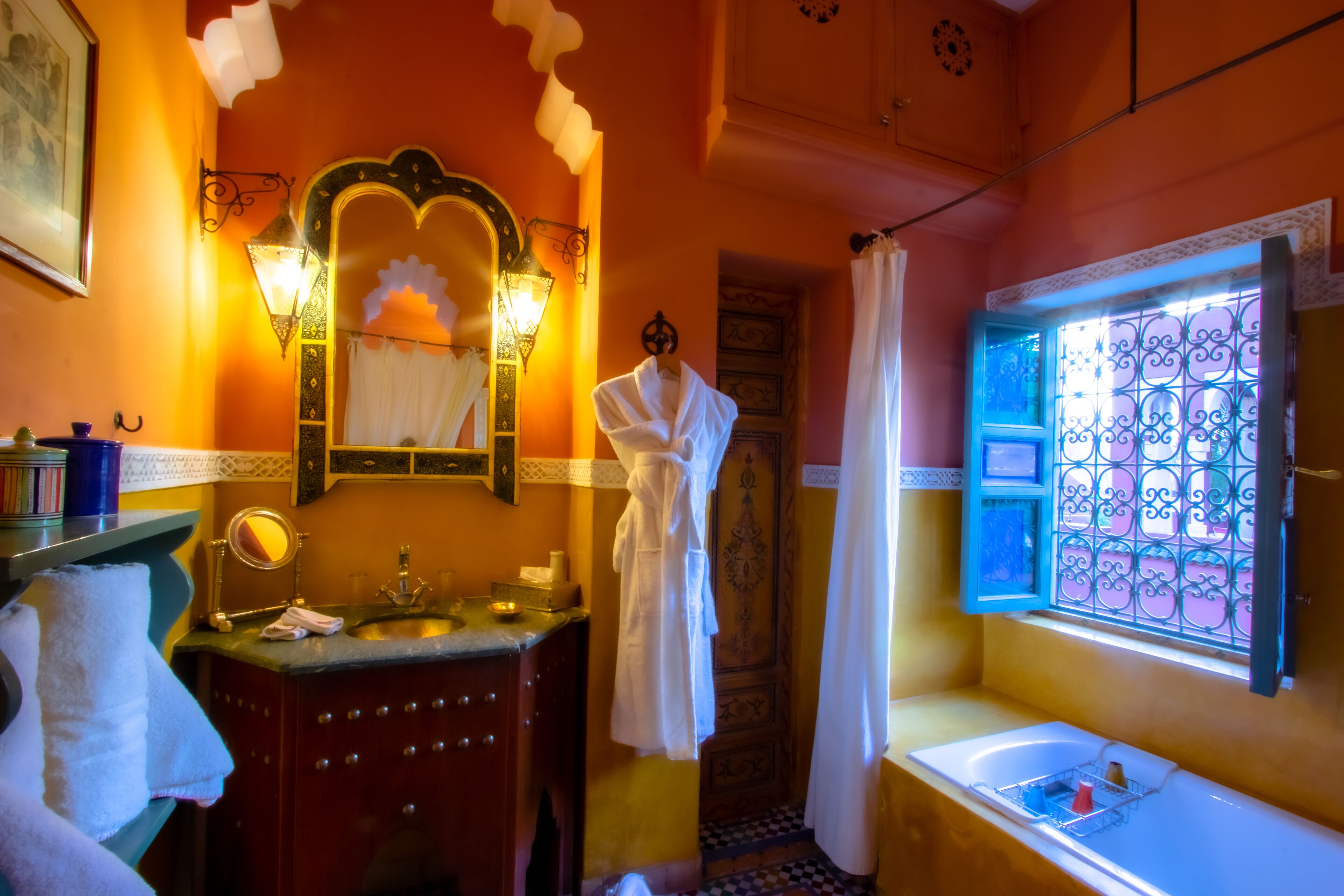A bathroom with a sink, mirror, and robe hanging on the wall.