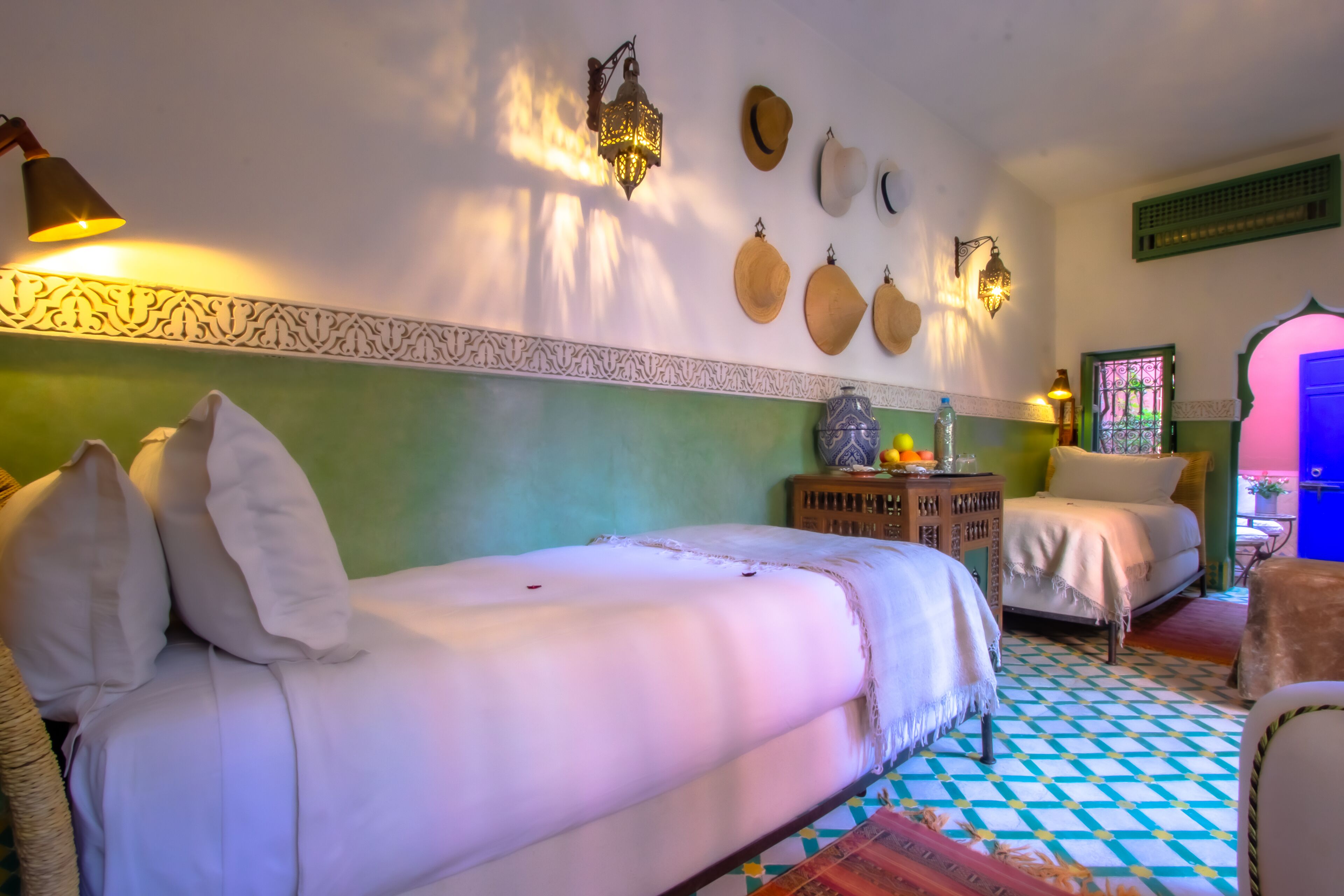 A room with a bed, two bedside tables, a wall-mounted lamp, a decorative wall hanging, and a patterned floor.