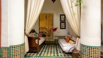 A room with a bed, a sofa, a small table, and a decorative wall.