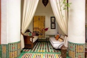A room with a bed, a sofa, a small table, and a decorative wall.