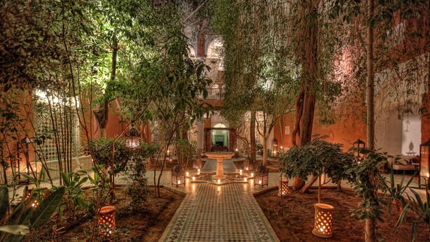 A courtyard with a central fountain, surrounded by trees and lanterns, leading to a building entrance. - Riad Kaiss by Anika (Marrakech)