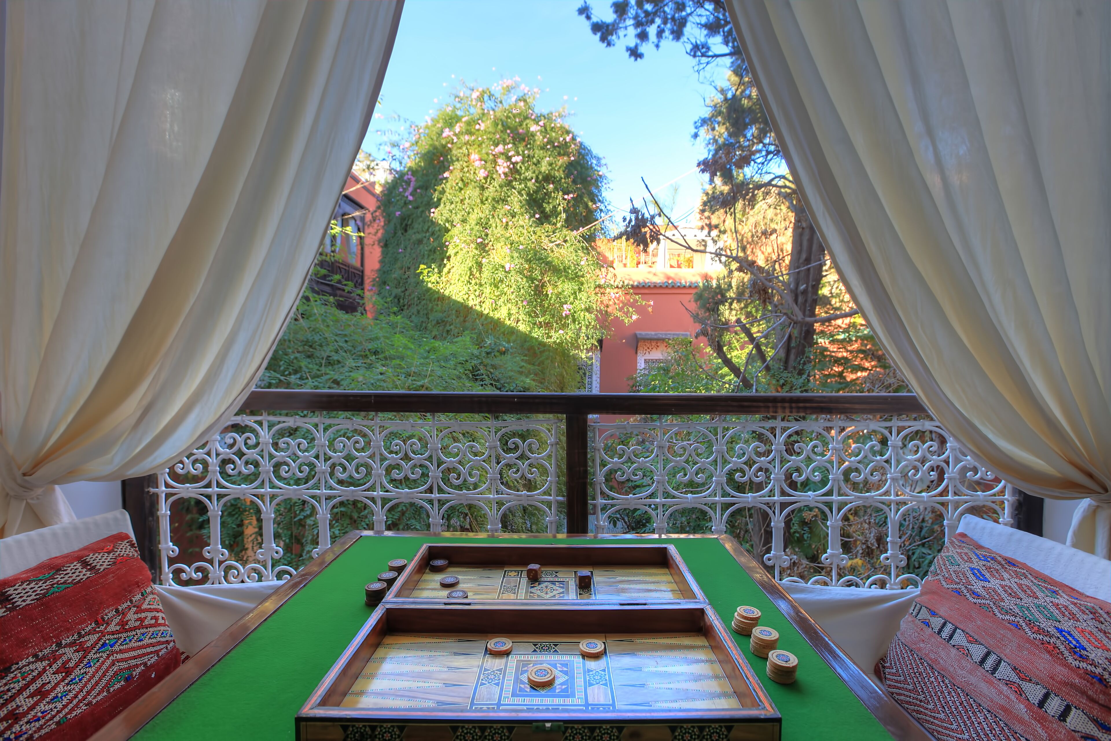 Quarto com mesa de futebol de bolso, janela com cortinas e vista para áreas verdes e edifícios.