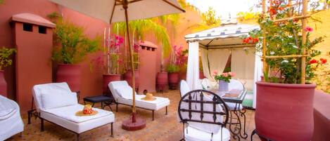 A patio area with white lounge chairs, a table, and a pergola with a white canopy.