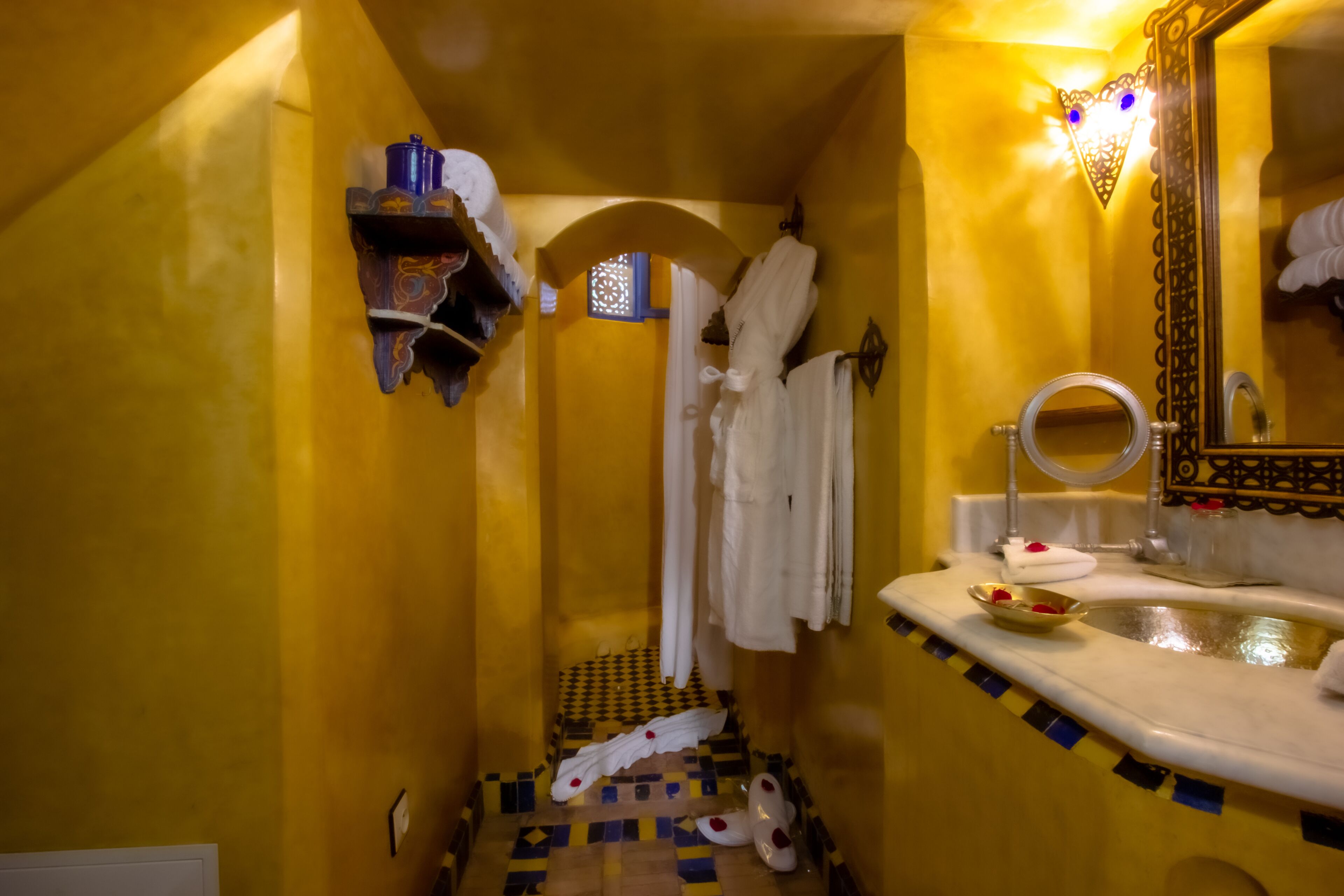 A bathroom with yellow walls, a checkered floor, a sink with a mirror, and a towel rack.