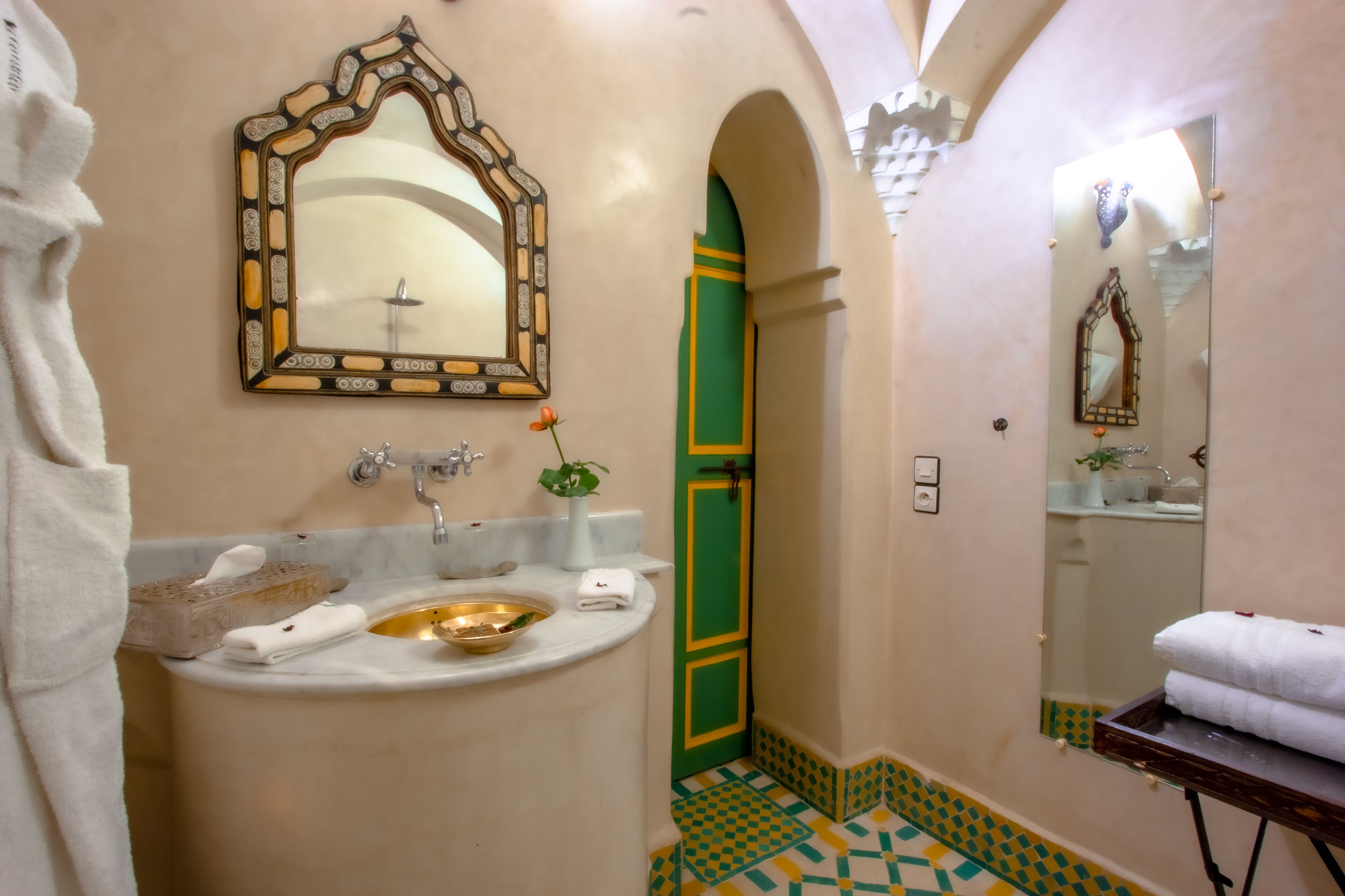 Une salle de bain avec un lavabo, un miroir et une porte verte.