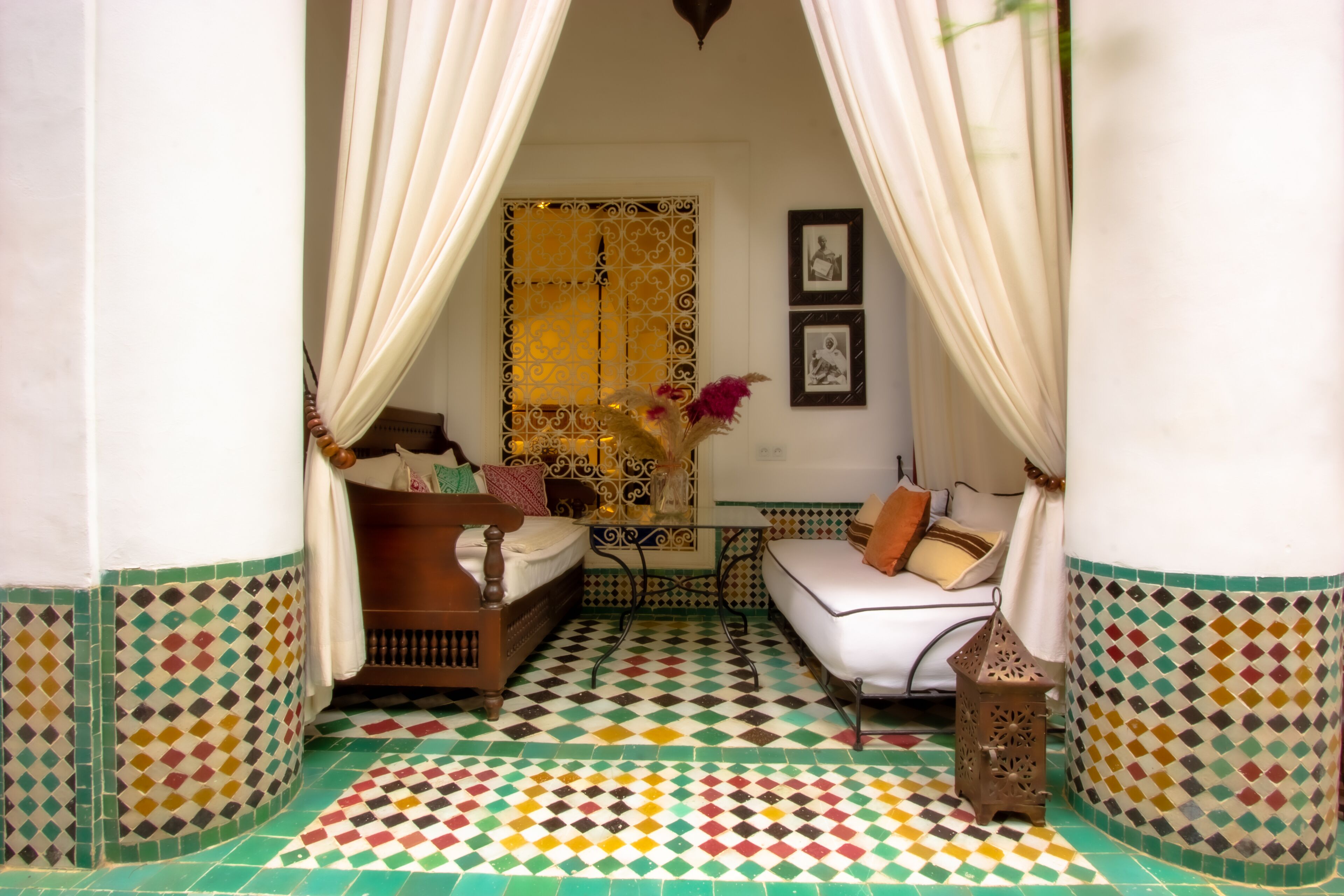 A room with a bed, a sofa, a table, and a decorative vase.