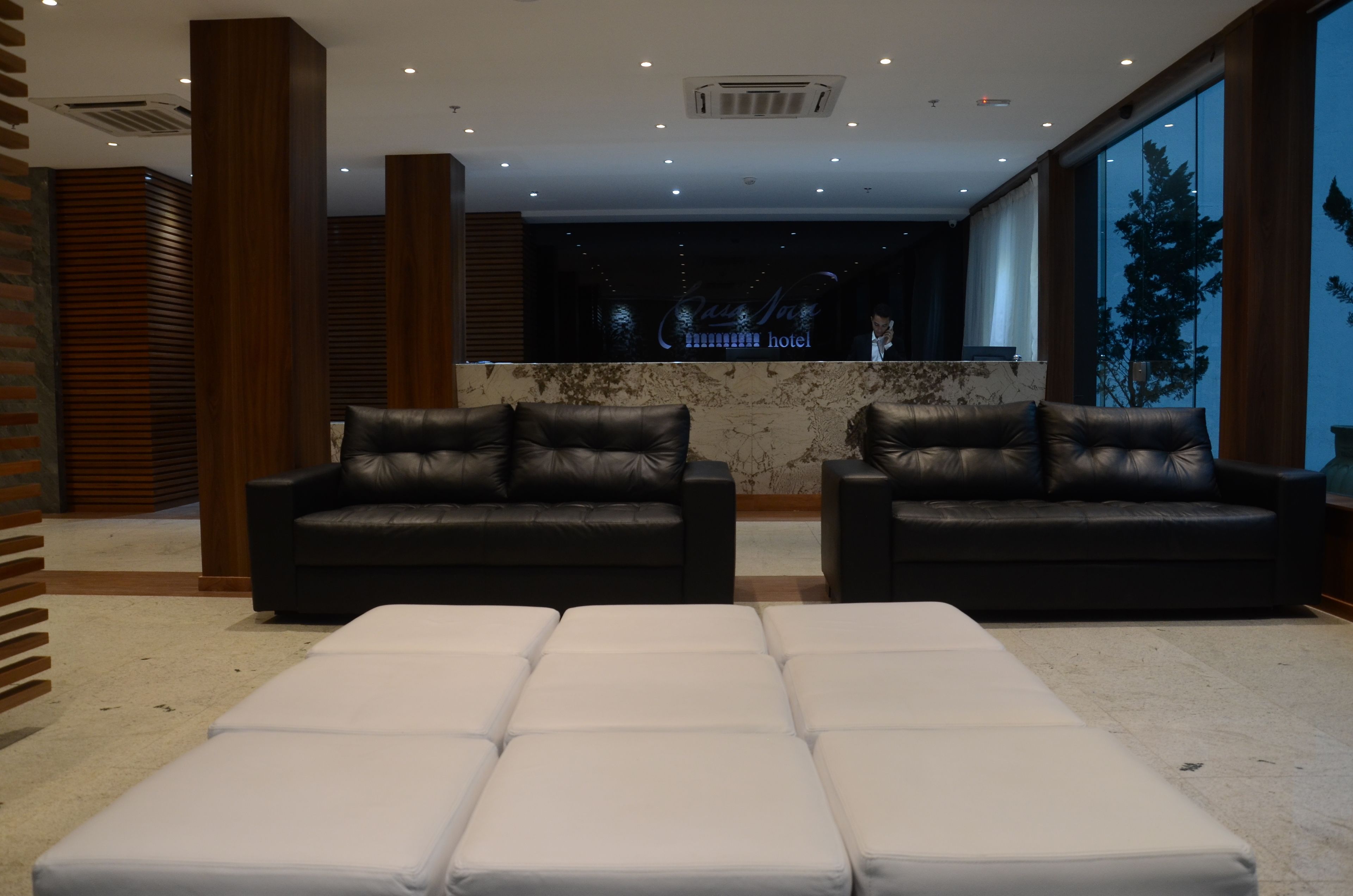 A modern lobby with two black leather sofas and a white ottoman in the foreground.