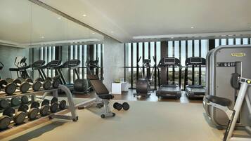 A modern gym with treadmills, elliptical machines, and a weight rack.