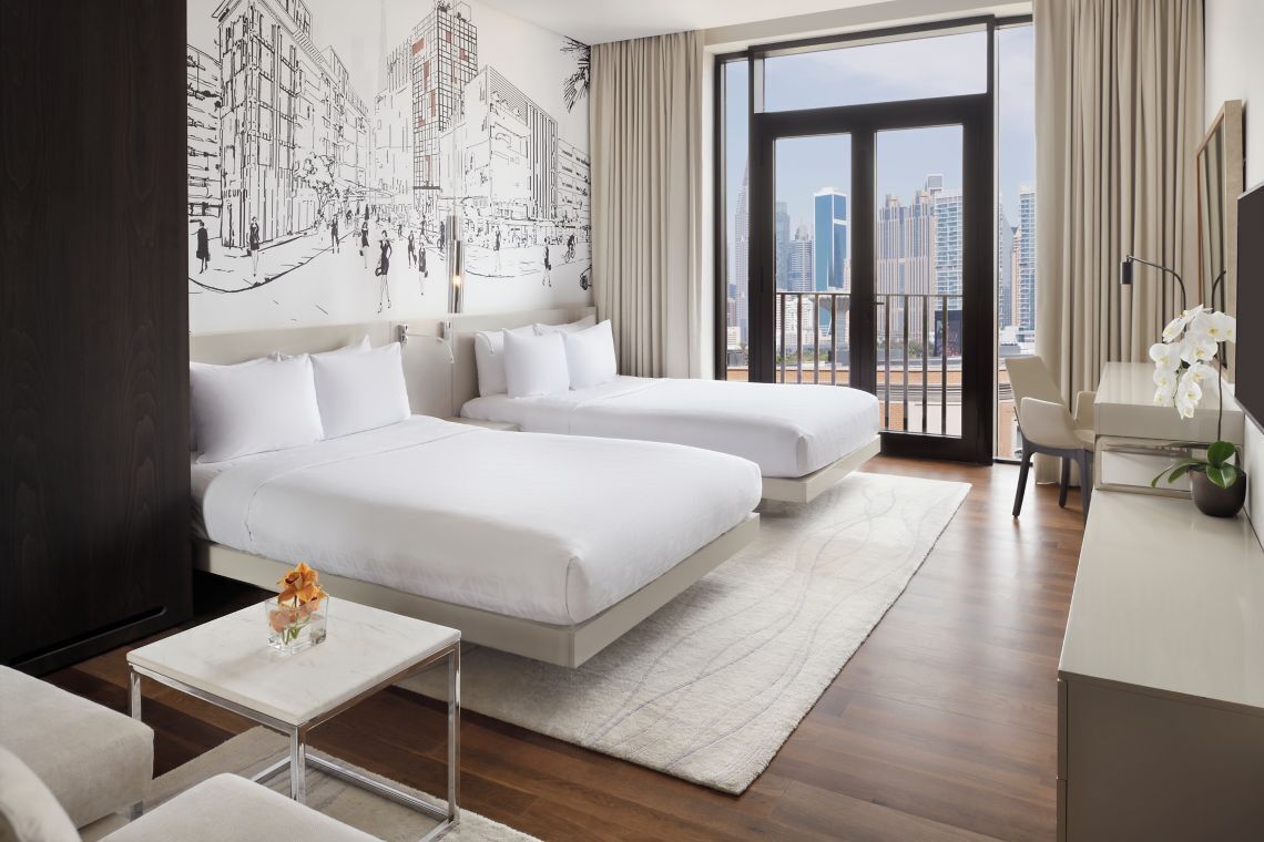 Una moderna camera d'albergo con un letto grande, una scrivania e vista sulla città.