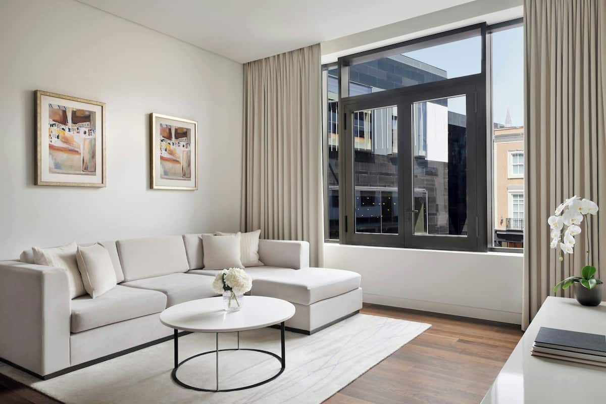 A modern living room with a white sofa, a round coffee table, and two framed artworks on the wall.