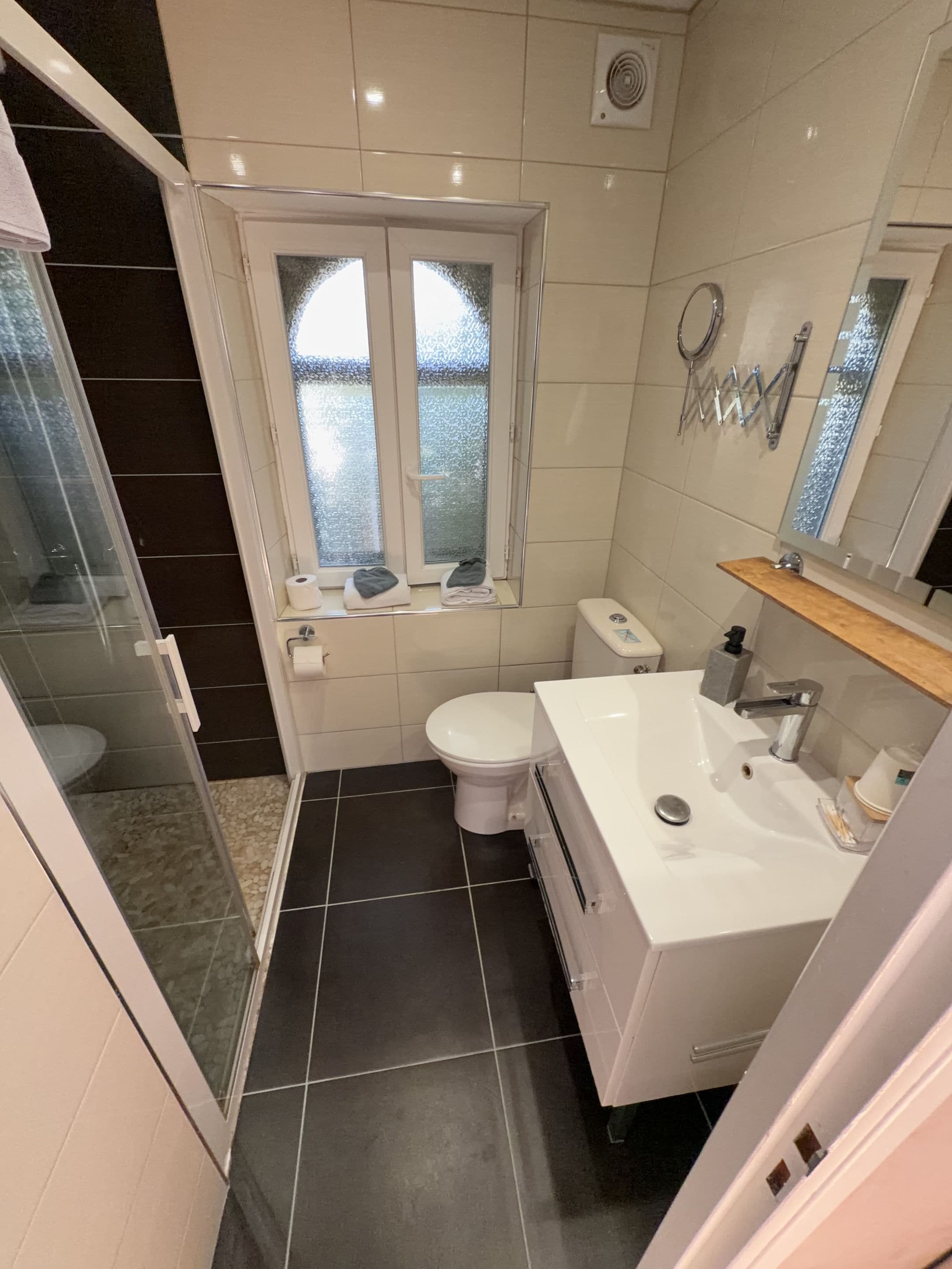 A bathroom with a toilet, sink, and a window with frosted glass.