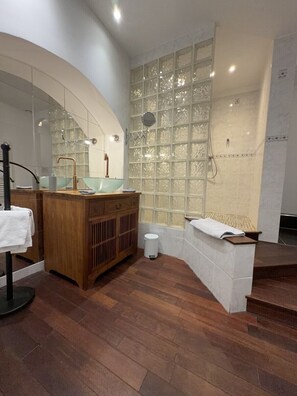 A modern bathroom with a wooden vanity, a glass sink, and a large mirror. - Le Corrigot (Pierry)