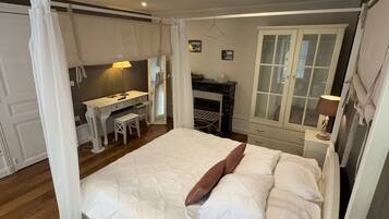 A bedroom with a large bed, a desk, and a fireplace.