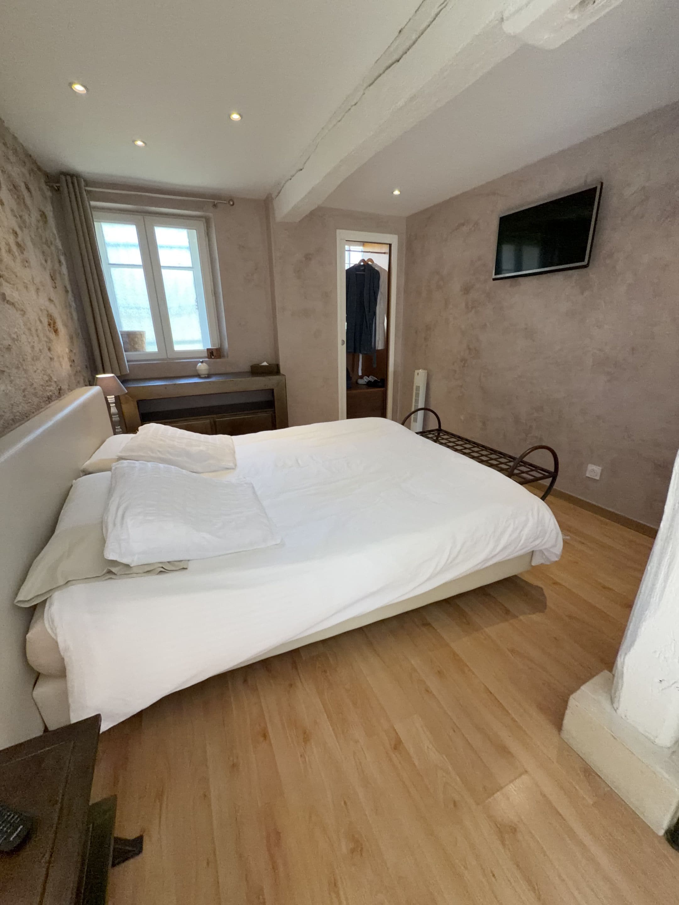 Une chambre à coucher avec un lit, un bureau, une chaise, une télévision et une fenêtre.