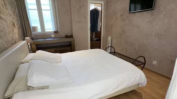 Une chambre à coucher avec un lit, un bureau, une chaise, une télévision et une fenêtre.