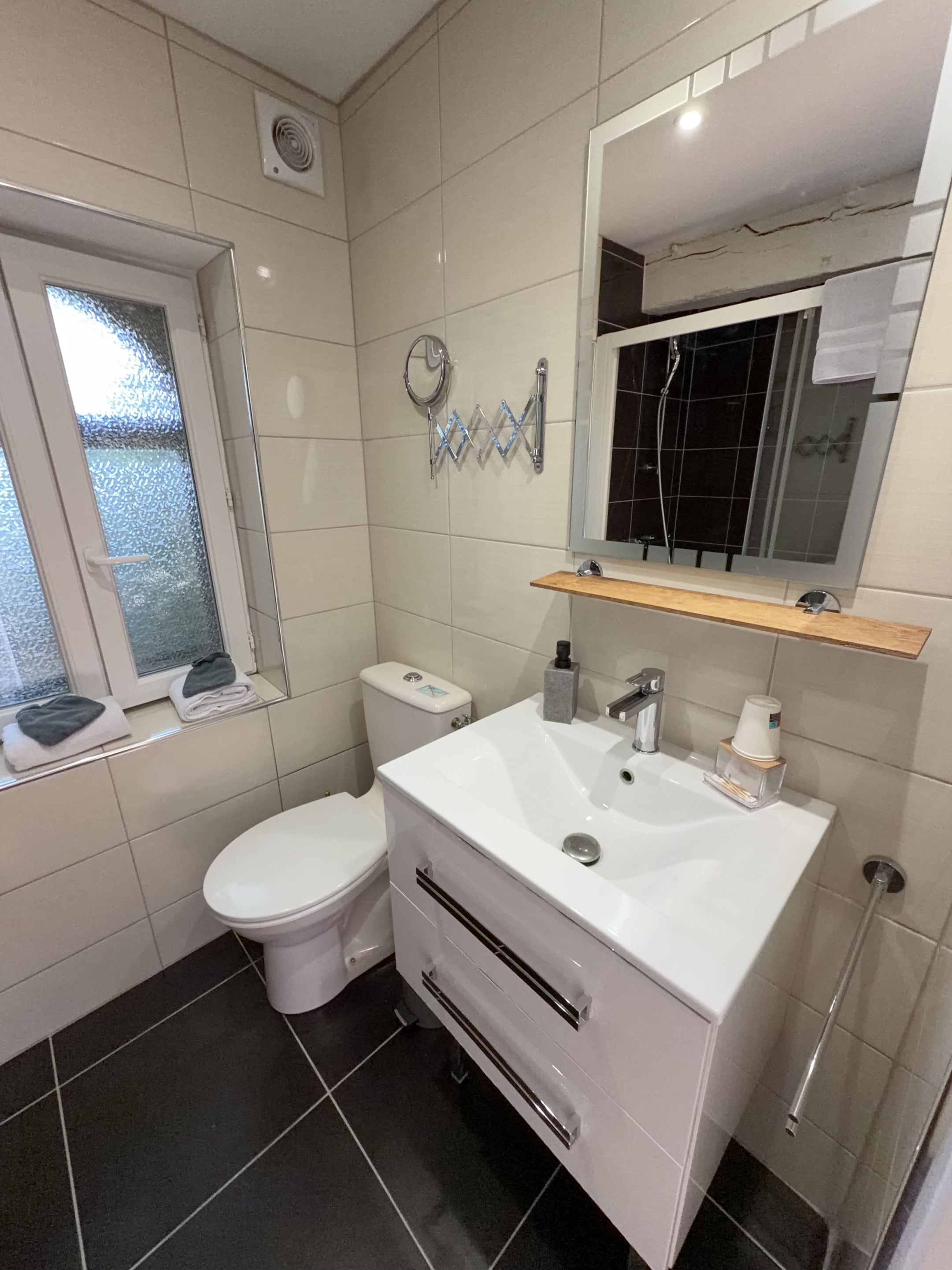 Een moderne badkamer met toilet, wastafel, spiegel en raam.